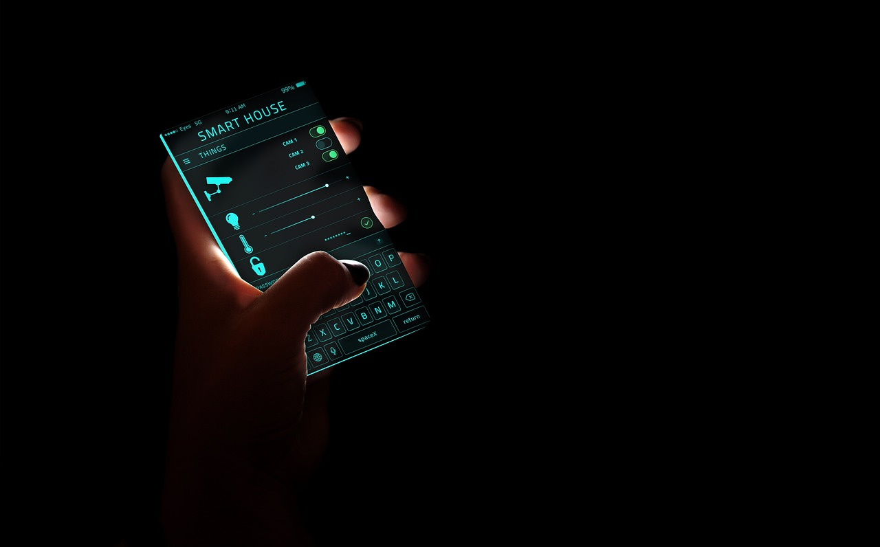 Hands holding a smartphone using a “smart house” app showing various home system automation controls