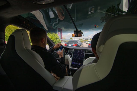 a view from the backseat of a man driving a Tesla