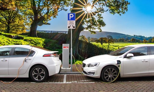 wo electric cars parked bumper-to-bumper plugged into EV charging stations