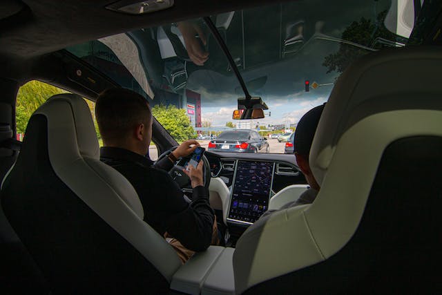  a view from the backseat of a man driving a Tesla
