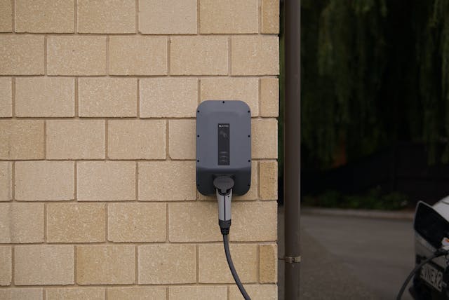 an EV charger installed in a driveway on the wall of someone’s home