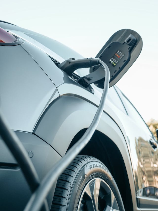 a close up of an EV charger plugged into a gray vehicle.
