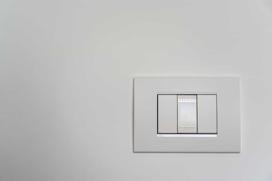 a white light switch unit with three switches on a white wall