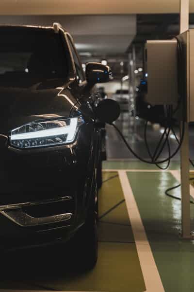  a black ev plugged into a charging station in a parking lot