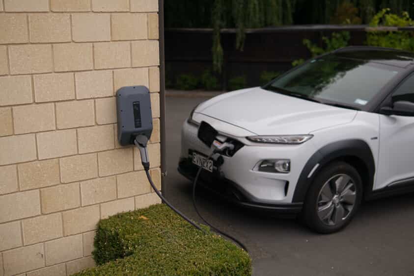 a white and black electric vehicle connected to a home charger.