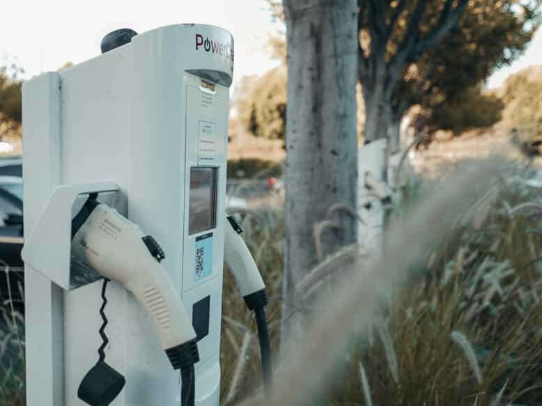 an ev charging station with two outlets in a rural parking lot with grass and trees