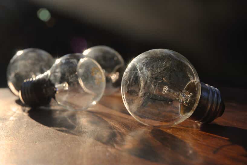 four old light bulbs lay on a wooden table